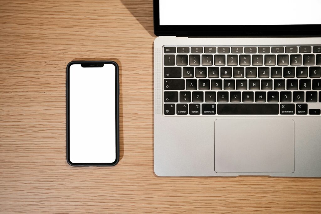 View from above of a smartphone next to an open laptop, representing Electronic Monitoring Policies in unionized workplaces in Ontario